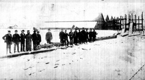 THE ICEMEN COMETH: During the winter of 1910 when the Princeton Ice Company was in full operation at what is now known as the Mountain Lakes Preserve, ice men lined up for an unknown photographer on a pier that was used to move “cakes” of ice to the incline elevator, right rear, for loading into the ice house that can be seen behind them. In the days before refrigeration, the Company served Princeton’s businesses and homes.(Photo Courtesy of the Historical Society of Princeton)