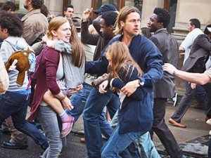 I’M GOING TO GET YOU ON A NAVY SHIP IN THE ATLANTIC OCEAN, WHERE YOU’LL BE SAFE: Gerry Lane (Brad Pitt, right) is struggling through the panic-stricken crowd with his wife Karen (Mireille Enos, left), who is holding their daughter Constance (Sterling Jerins). Gerry is holding onto their other daughter Rachel (Abigail Hargrove) as they work their way to the embarkation point where Gerry’s family can be transported to the Navy’s safe ship, while Gerry goes off to help save the world from the pandemic.