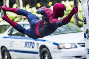 I HOPE THAT COP IN THE CAR DOESN’T GIVE ME A TICKET FOR HITCHHIKING: Spider-Man, aka Peter Parker (Andrew Garfield) hitches a ride on a police van in one of his crime fighting episodes.