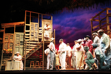 “SUMMERTIME, AND THE LIVING IS EASY”: Clara (Brandie Sutton) sings a lullaby to the baby cradled in her arms in the opening scene of the opera “Porgy and Bess,” while the people living in Catfish Row go about their business in the early summer evening.(Photo by Costa Papastephanou)