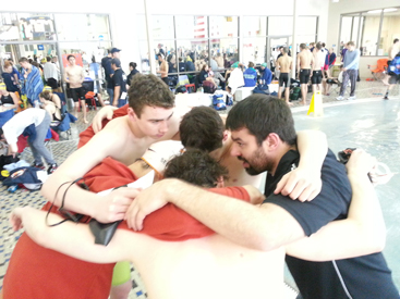 LOCKED IN: Coach Miles Cava, right, and a relay team for the Princeton Tigers Aquatics Club (PTAC) interlock arms as they get fired up before a recent meet. PTAC is based at Princeton University’s DeNunzio Pool and also boasts a water polo program. Cava, a Princeton High alum and former swimmer for the Princeton University men’s team, has been a coach with the program since 2010.(Photo Courtesy of PTAC)