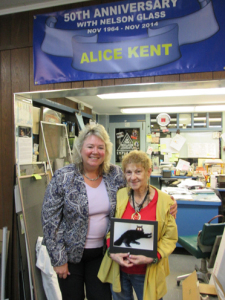 LOYALTY AND LONGEVITY: “I really like my job because it is so diversified, and every day is different. You can always count on something interesting happening.” Alice Kent (right), general manager of Nelson Glass & Aluminum Co., is celebrating 50 years with the company. She is shown with owner Robbie Nelson and a photo of Alice’s cat, Taz.