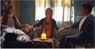 NOW HOLD MY HANDS WHILE I TRY TO CONTACT QUINN’S MOTHER: Elise (Lin Shaye, center) begins a séance in an effort to help Quinn (Stefanie Scott, left) communicate with her dead mother while her father (Dermot Mulroney) looks on. When Quinn’s attempts to contact her mother  on her own stirred up a host of frightening paranormal events, Elise agreed to come out of retirement to help Quinn communicate with her mother.(Photo by Matt Kennedy)